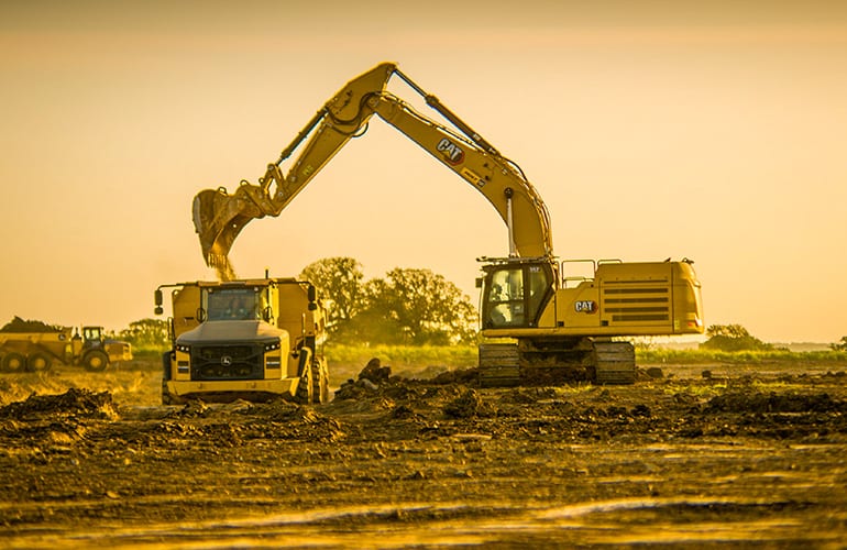 an autonomous loader drops dirt into a dump truck. Bedrock Robotics is making such equipment autonomous.