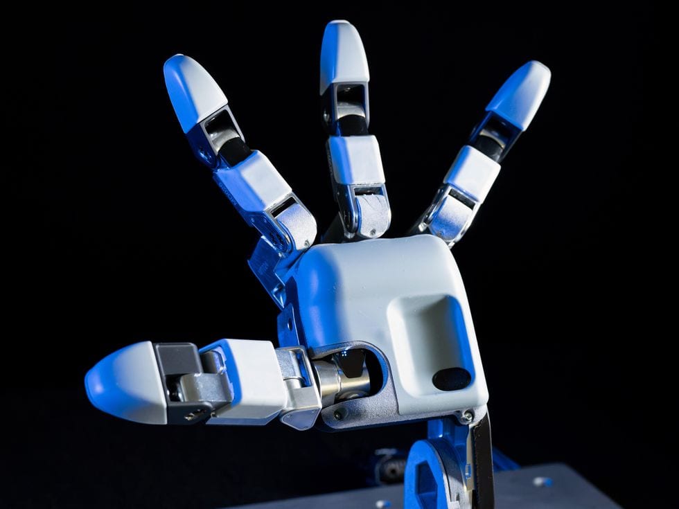 Close-up of a splayed robotic hand with three fingers and a thumb.