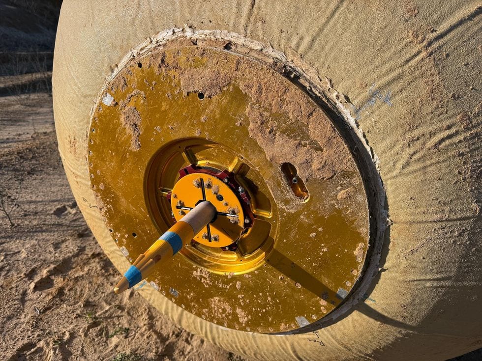 Close-up of a needle-like rocket protruding from the payload bay of a large robotic ball.